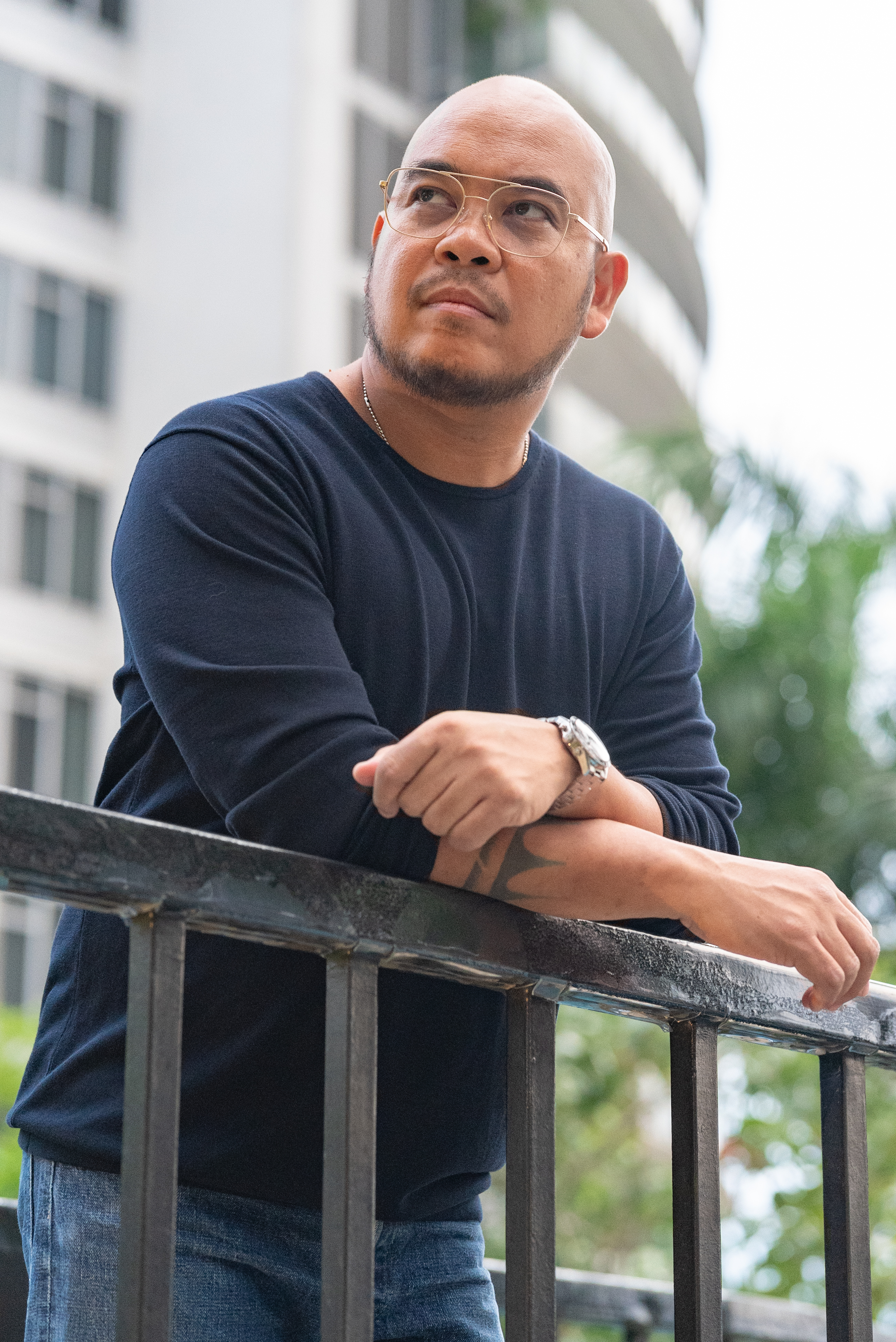 Julian P. Tarrobago Jr. leaning on a railing and looking up, outdoors against a city backdrop