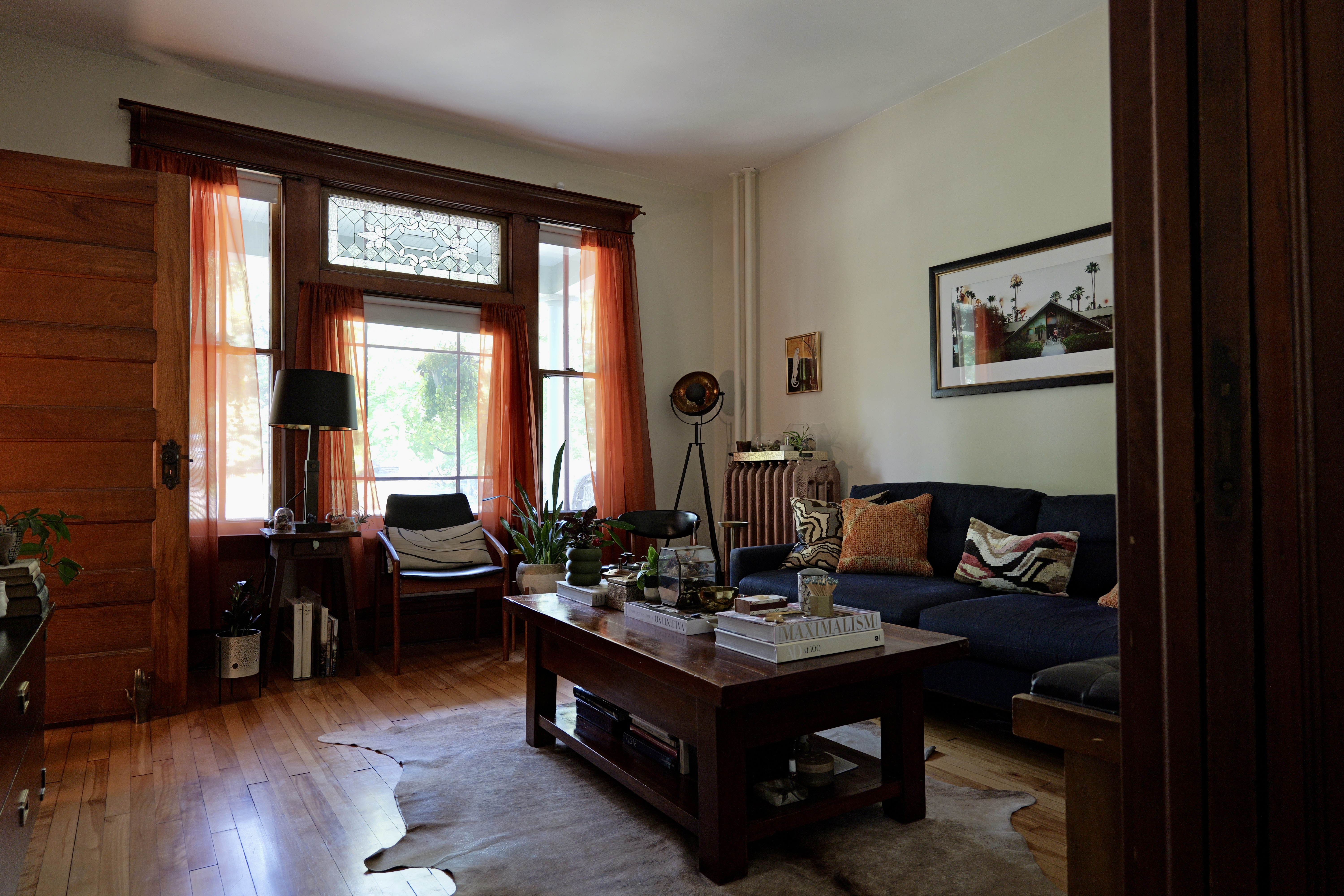 A living room designed by Lauren Hunter Design, with a navy sectional sofa, patterned throw pillows, warm wood trim, and a cowhide rug